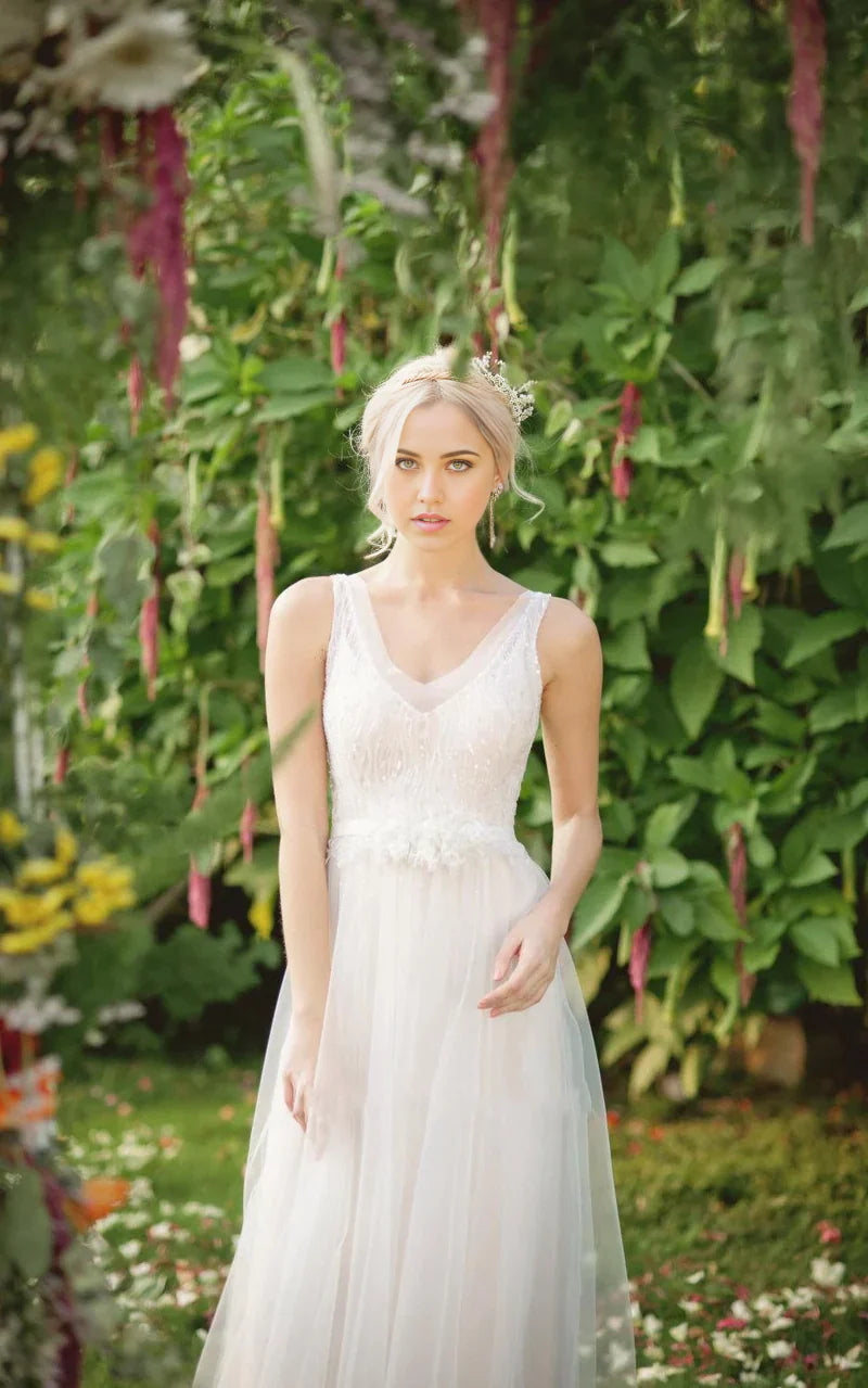 Close-up of the bodice and V-neckline of the wedding dress, showing lace, beading, and sequins.