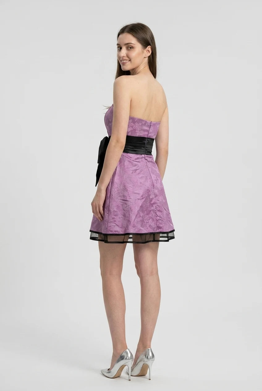 Model in a light-colored V-neck A-line dress with spaghetti straps, showing back detail.