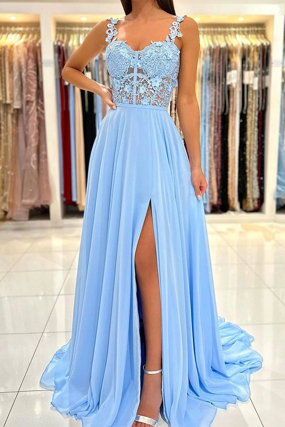 Elegant woman wearing a blue spaghetti strap corset prom dress with appliques.