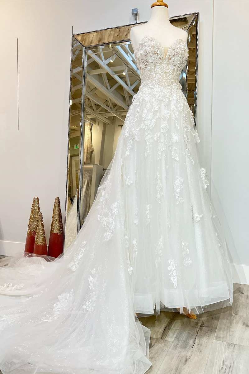 Elegant A-line wedding dress with applique details and a sweeping train, front view.