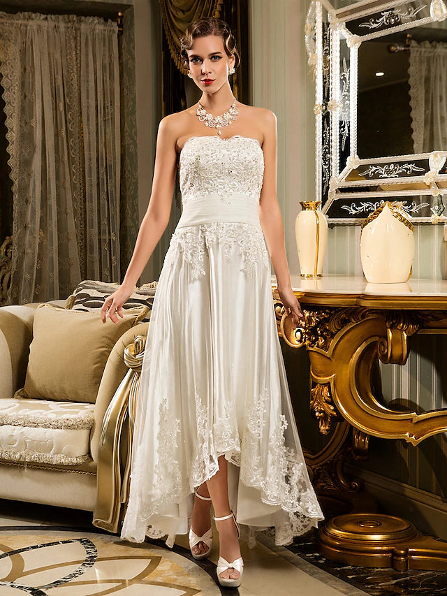 Front view of a white asymmetrical A-line wedding dress with strapless sweetheart neckline and lace appliques.