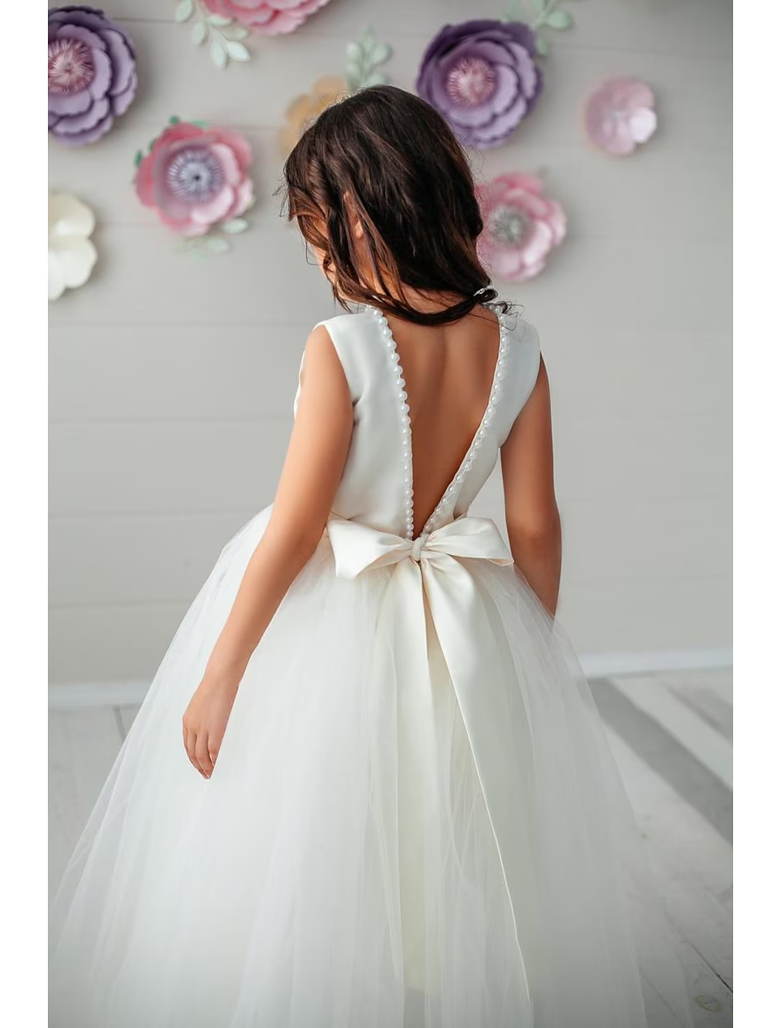 Back view of the satin ball gown showing the open back and a large bow detail.