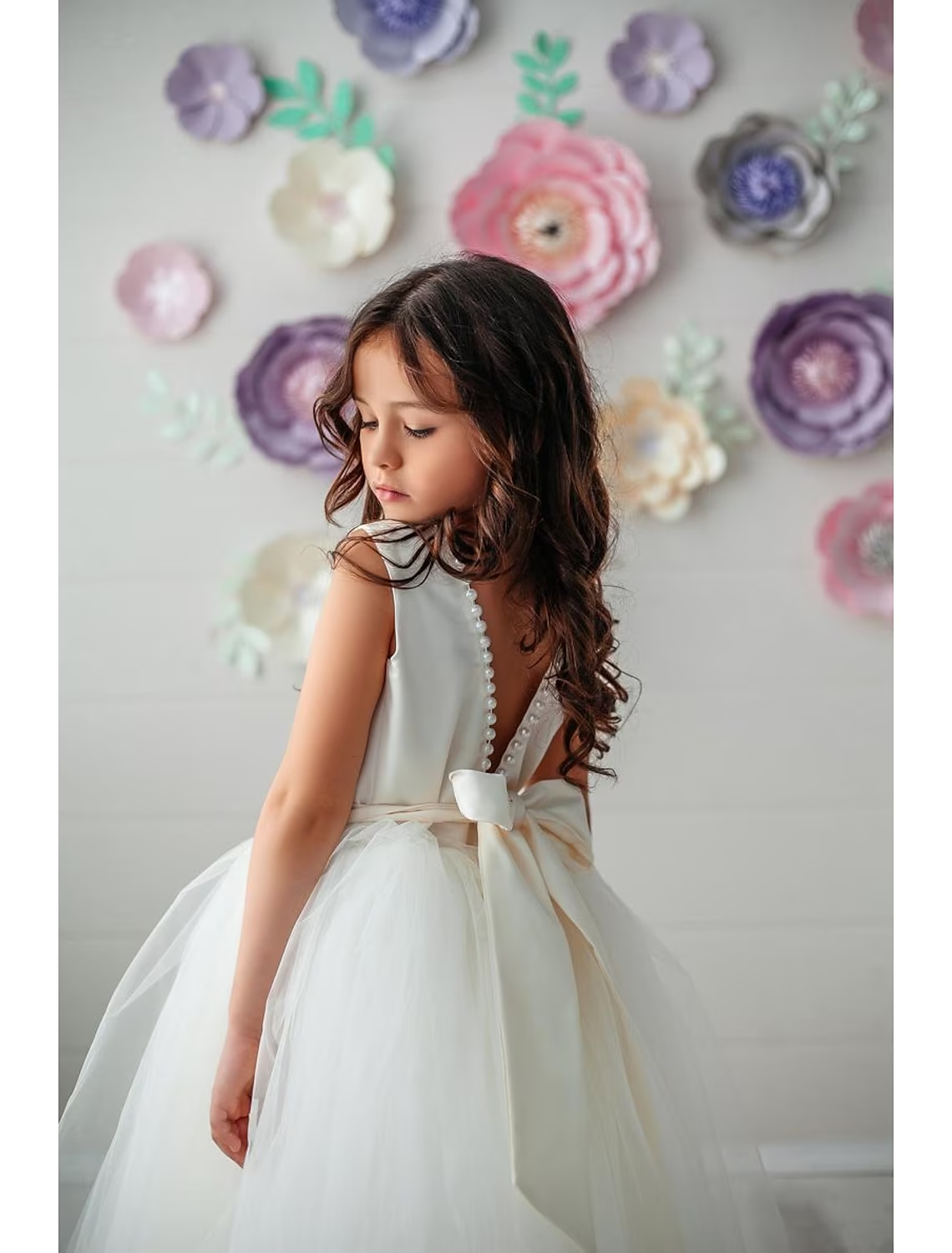Close-up of the delicate bow detail on the open back of the satin dress.