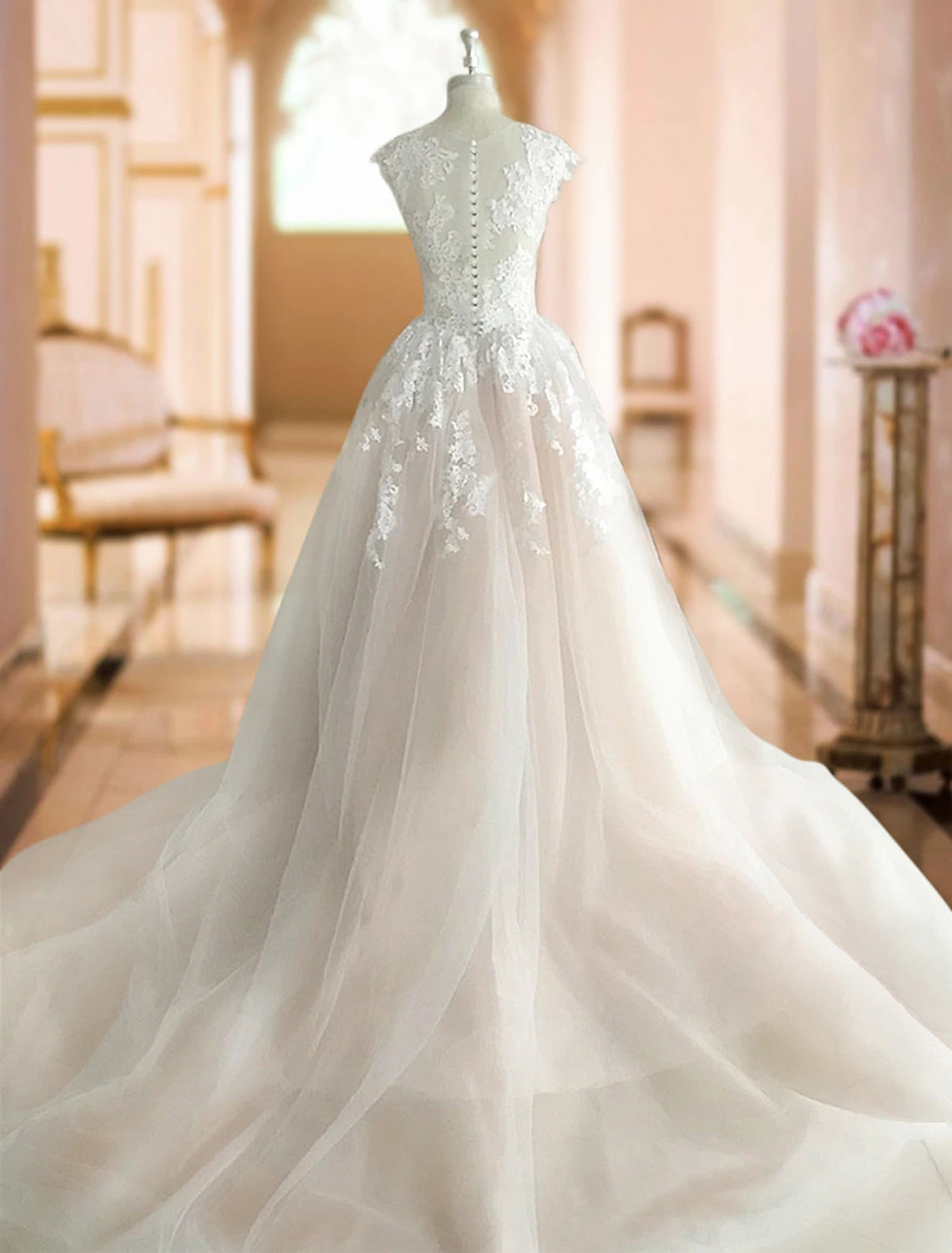 Back view of bridal ball gown showing lace appliques, buttons, and court train.
