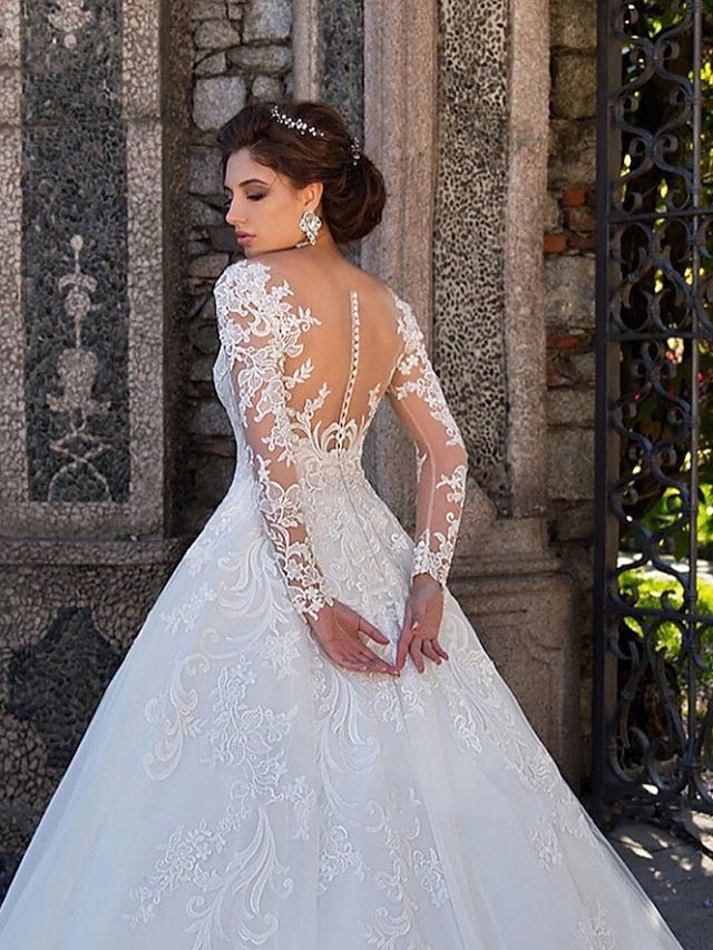 Side profile of a bride in a white ball gown wedding dress, highlighting the full skirt and long sleeves.