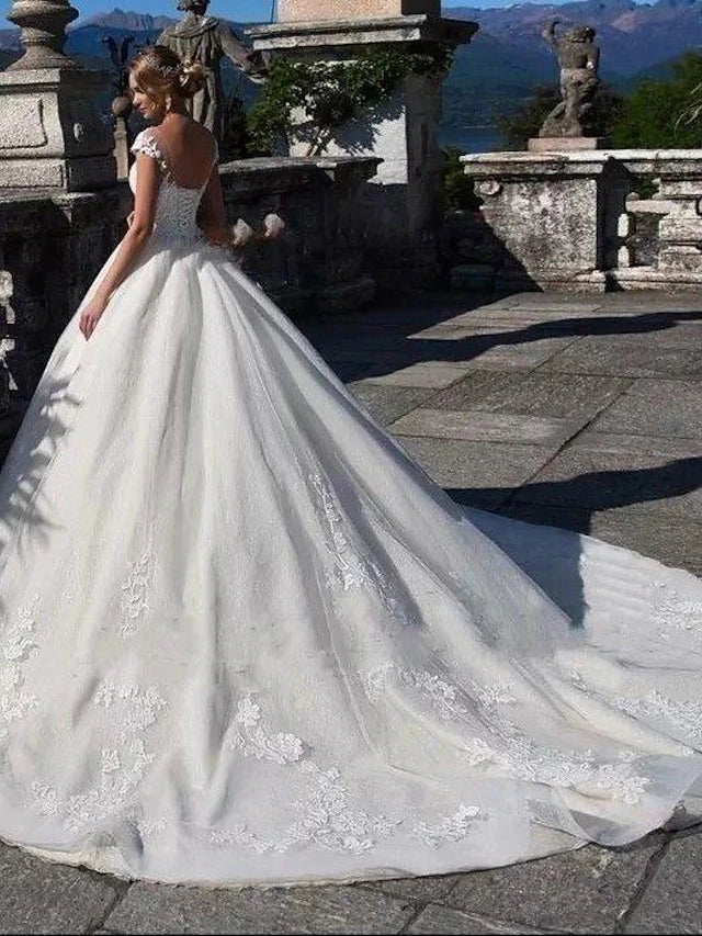 Back view of a white wedding ball gown showing open back and chapel train.