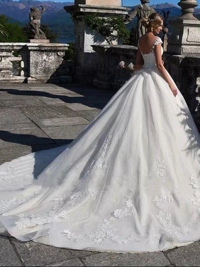 Side view of a bride wearing a white cap sleeve ball gown wedding dress.