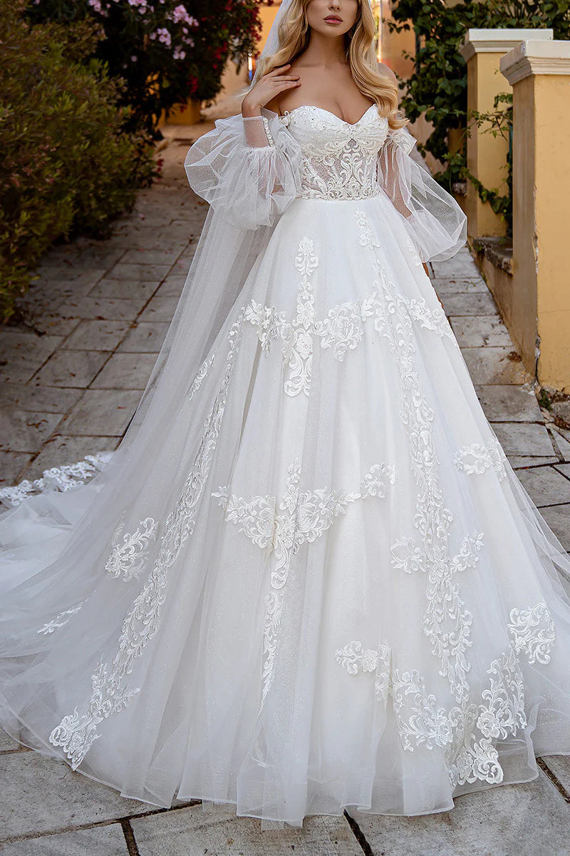 Elegant white ball gown wedding dress with sweetheart neckline, lace appliques, and long sleeves.