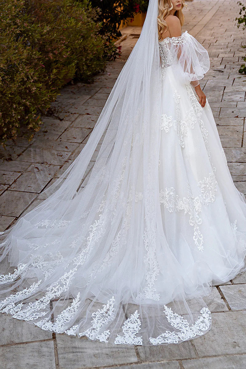 Side view of a white ball gown wedding dress, showing lace appliques on long sleeves and bodice.