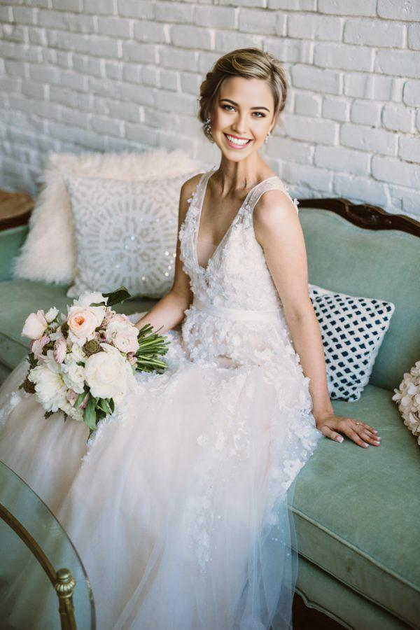 Close-up of the V-neckline and lace applique on an ivory wedding dress.
