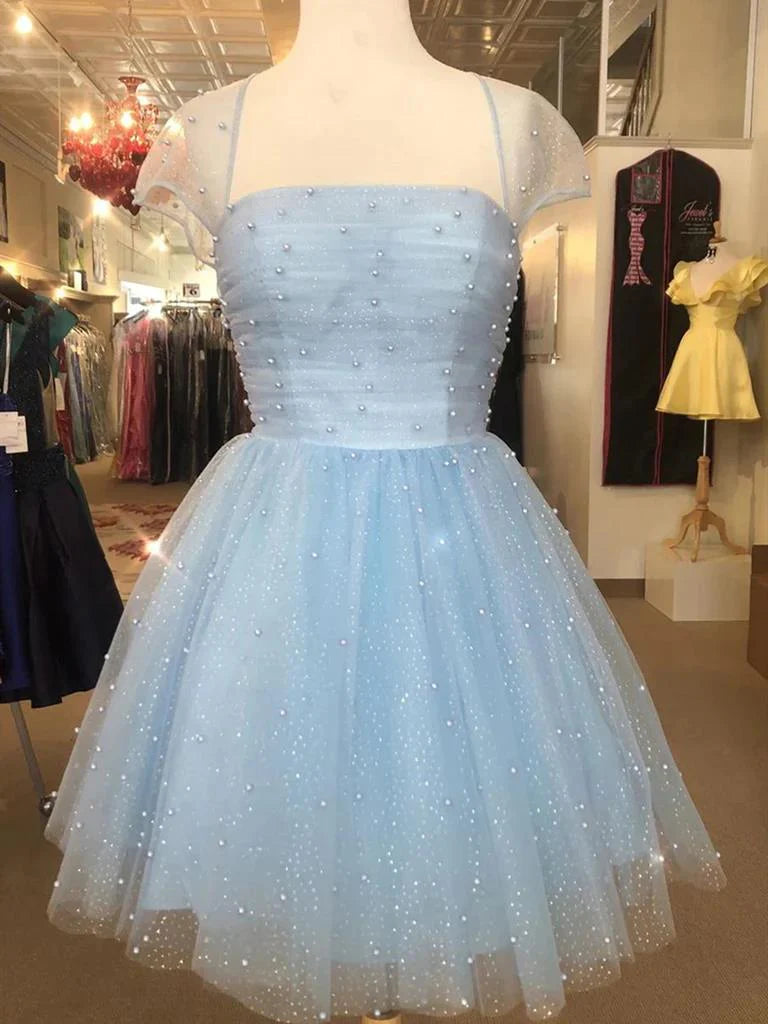 A woman wearing a short beaded A-line prom dress with cap sleeves and a V-neck.