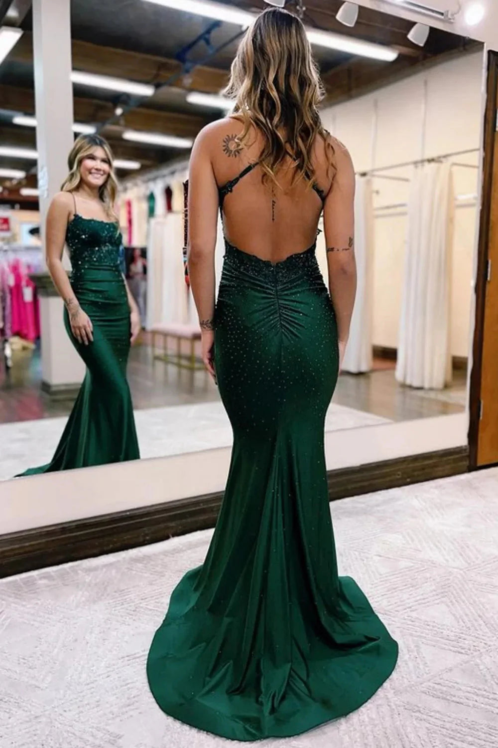 Back view of the dark green V-neck prom dress, showcasing its flowing silhouette and detailed embellishments.