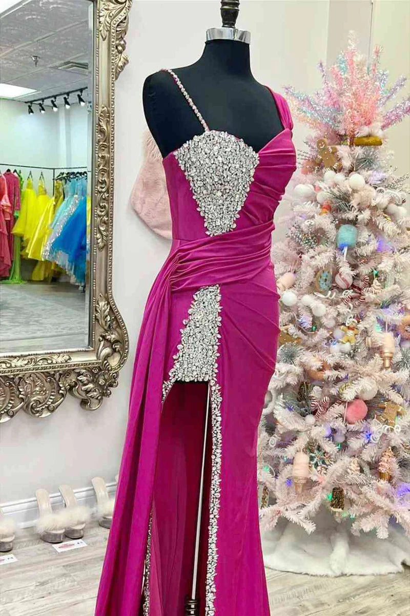 Woman posing in a long beaded asymmetrical formal gown.
