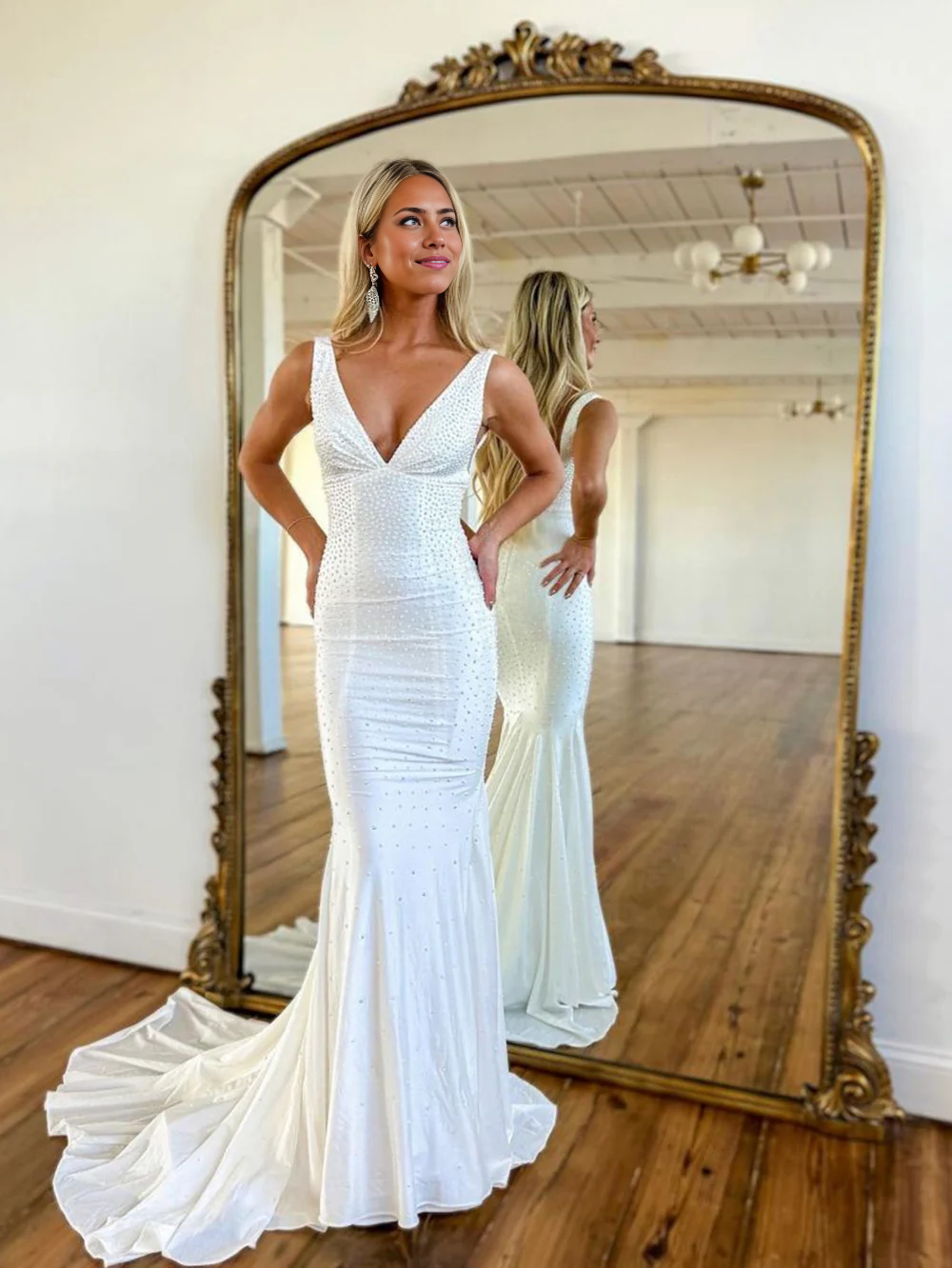 Full-length view of a woman wearing an elegant mermaid beaded deep V-neck satin long prom dress.