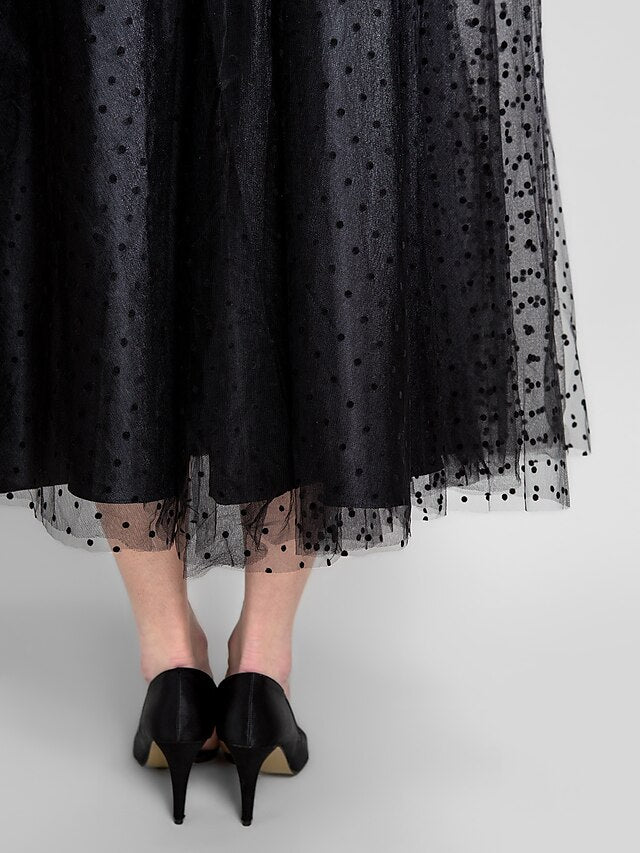 Detailed view of the delicate tulle skirt and ribbon sash on the black ball gown.