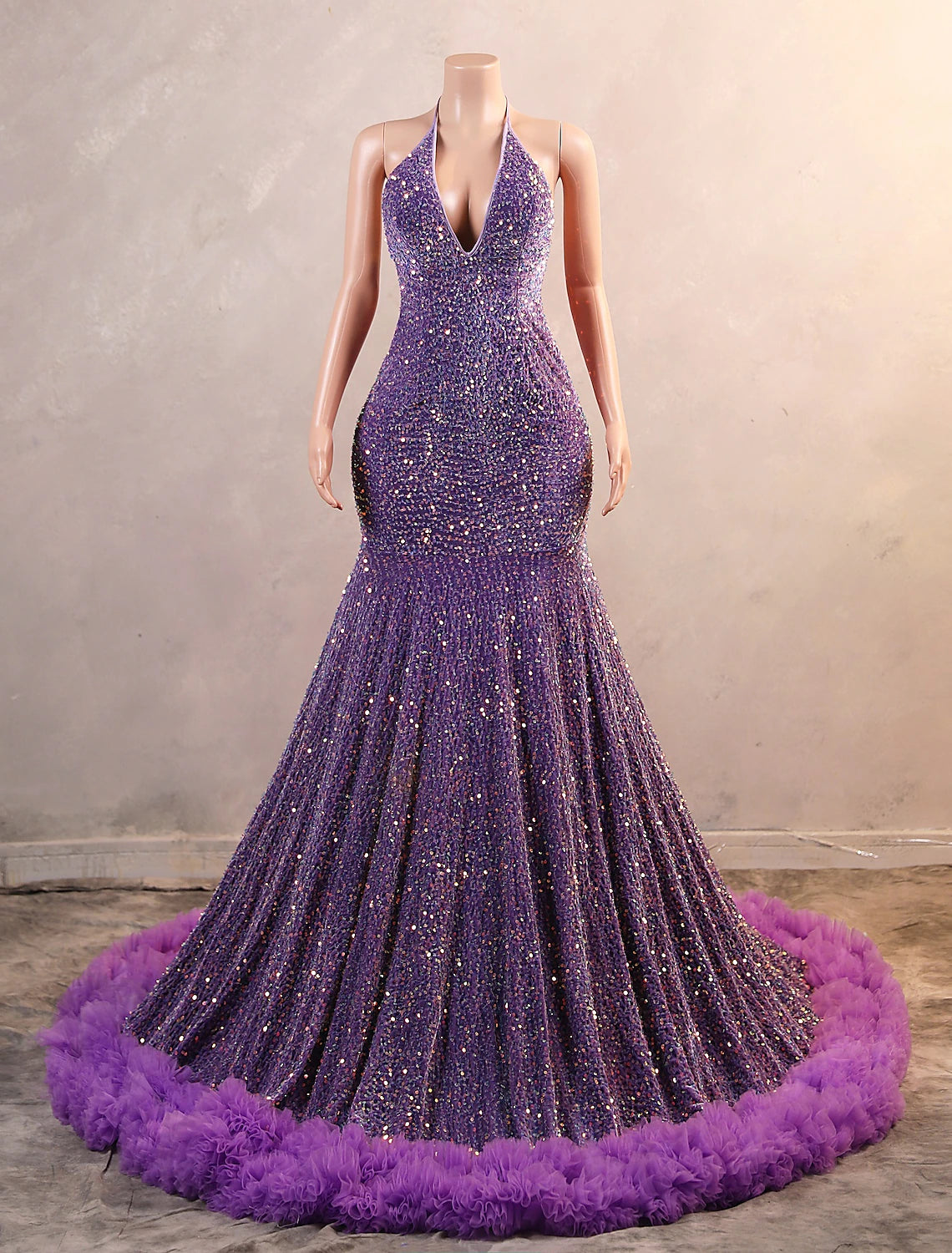 Full-length view of a woman wearing a black sequined mermaid evening gown with fringe.