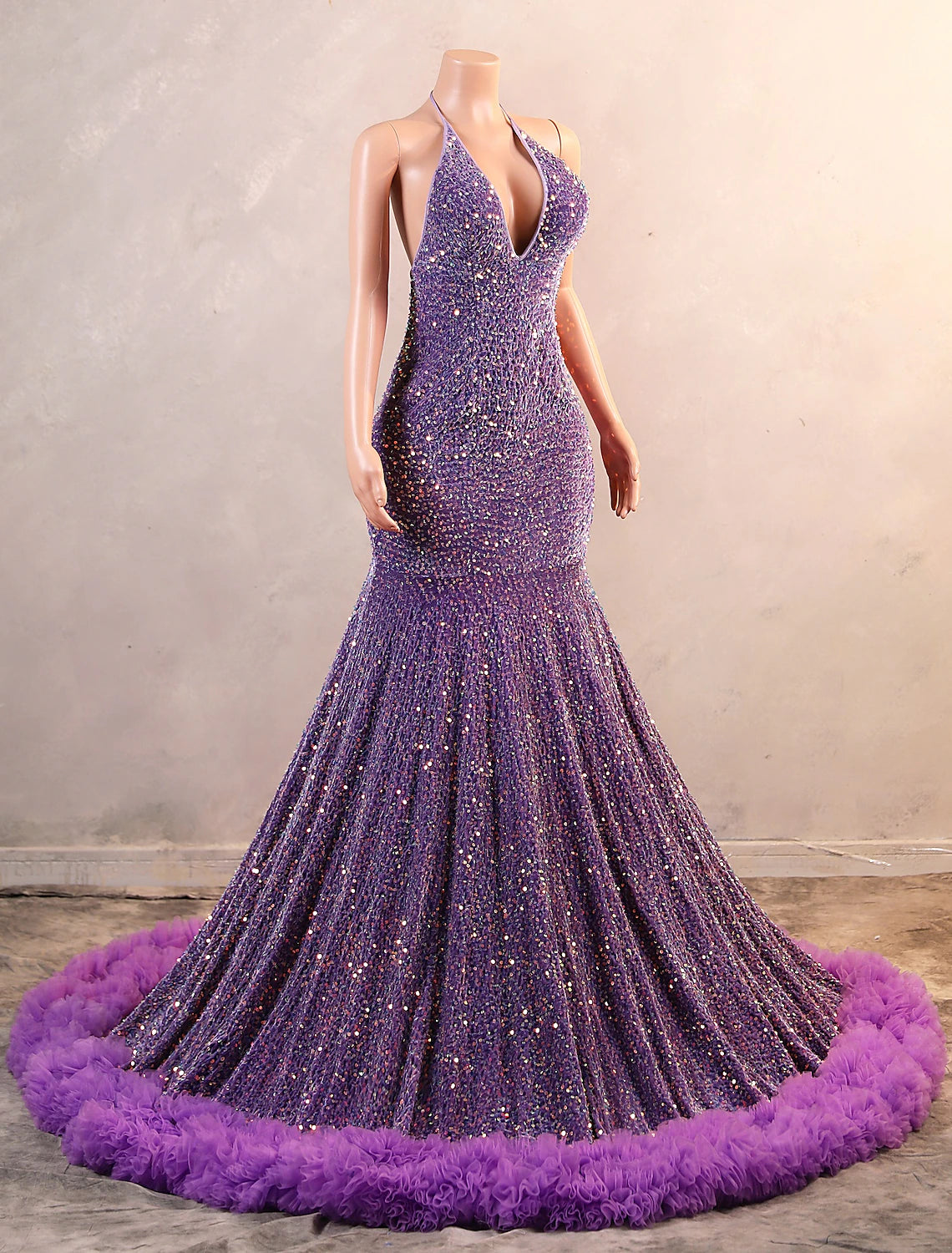 Side view of a woman in a black sequined mermaid gown, showing the trumpet flare and fringe details.