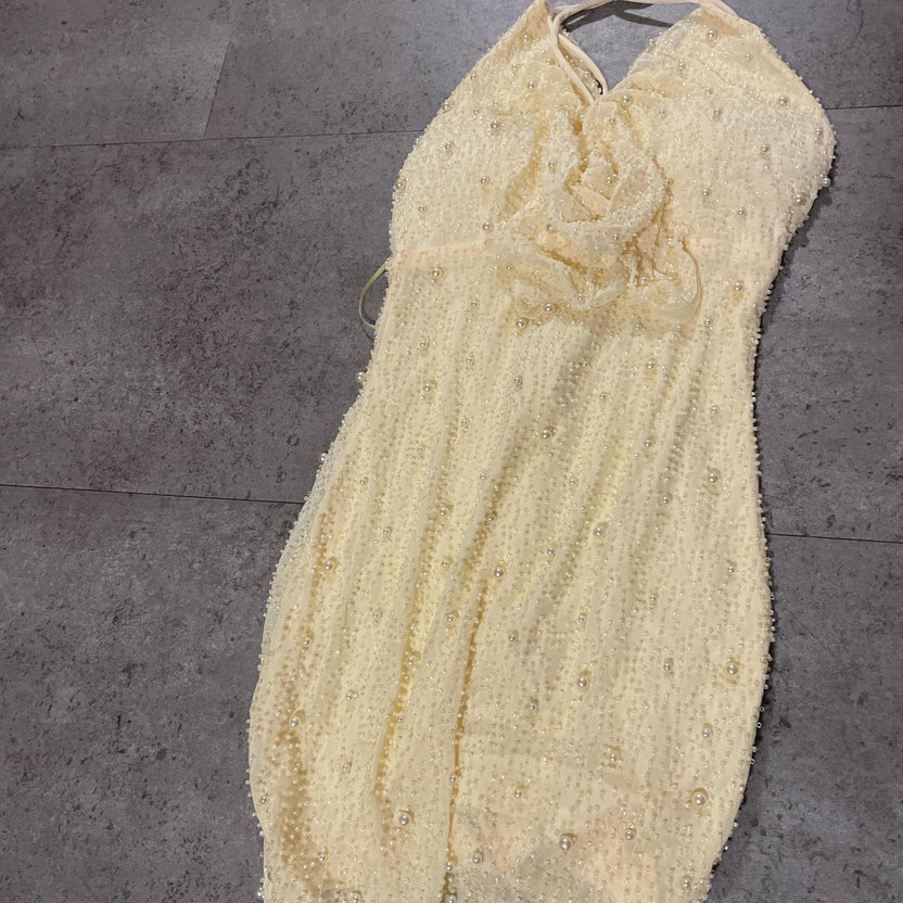 Close-up of the pearl embellishments on the pale yellow bodycon dress.