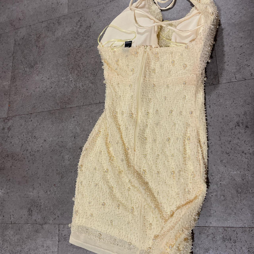 Detail of the halter cowl neckline and pearl details on the pale yellow dress.