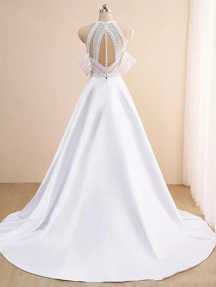 Model wearing a boho lace off-shoulder wedding dress on a beach.