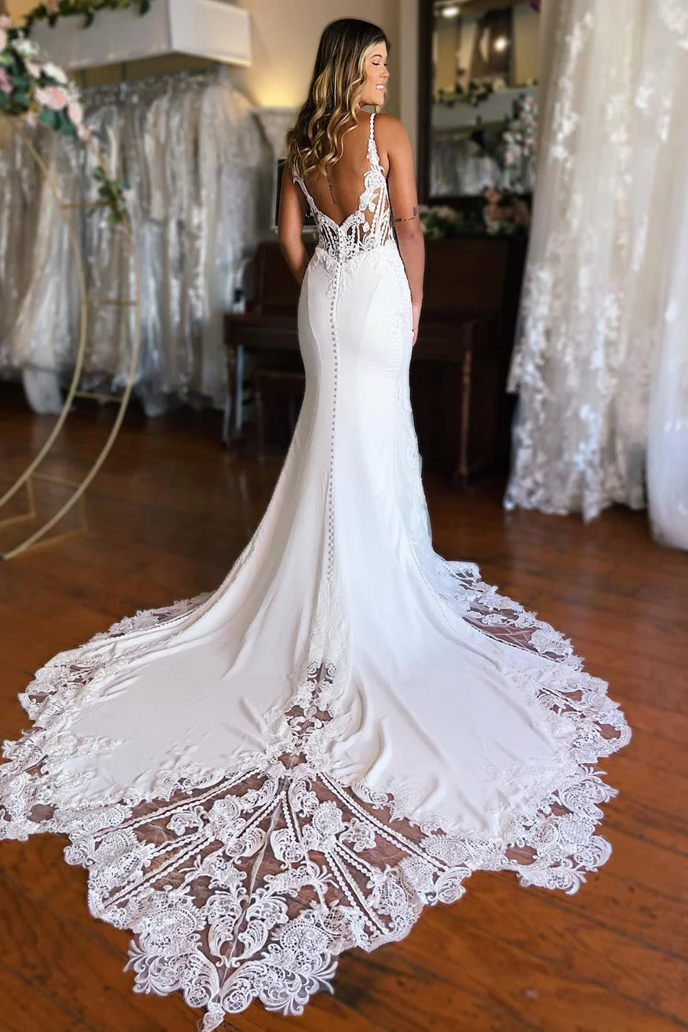 Side view of a bride wearing a long white lace mermaid wedding gown.
