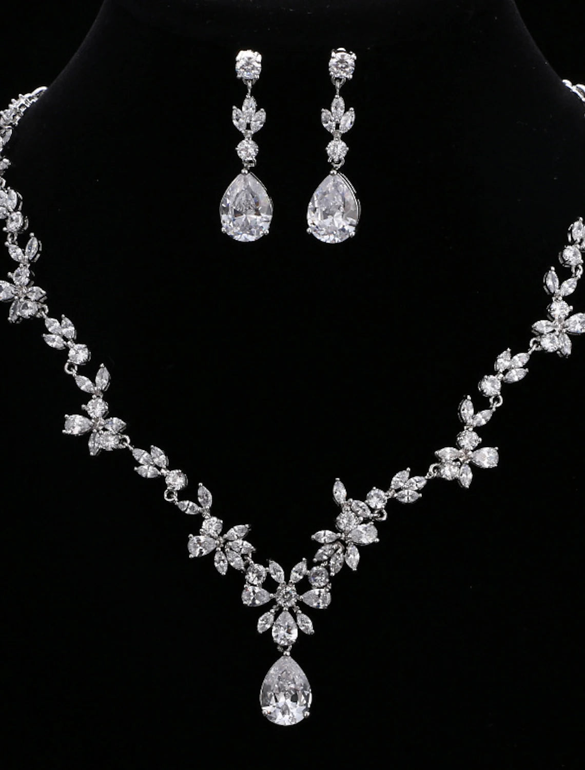 Woman wearing a silver-toned cubic zirconia necklace and matching drop earrings.