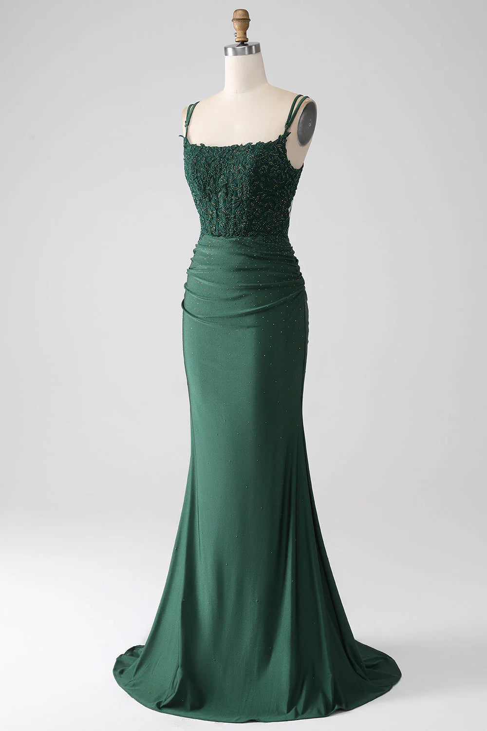 Side view of a woman wearing a dark green spaghetti strap mermaid dress.