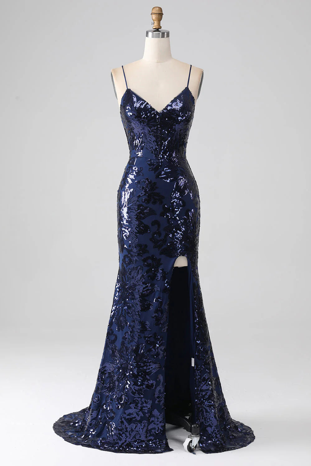 Model wearing a dark navy mermaid prom dress with spaghetti straps and a high slit.