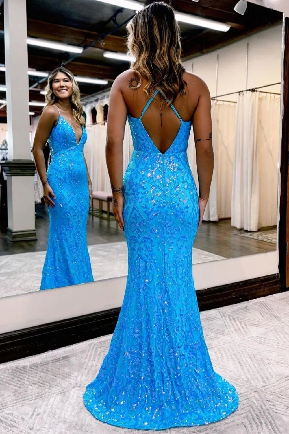 Woman posing in an elegant blue deep V-neck mermaid prom dress.