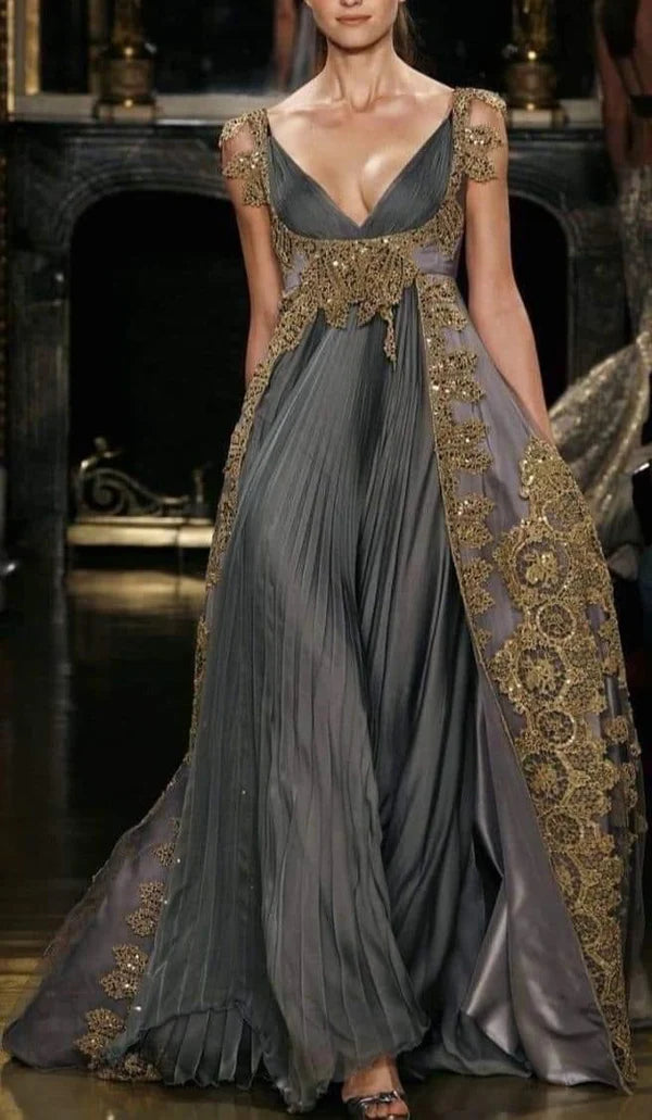 Woman wearing a charcoal gold embellished V-neck A-line gown with cap sleeves and a side train.