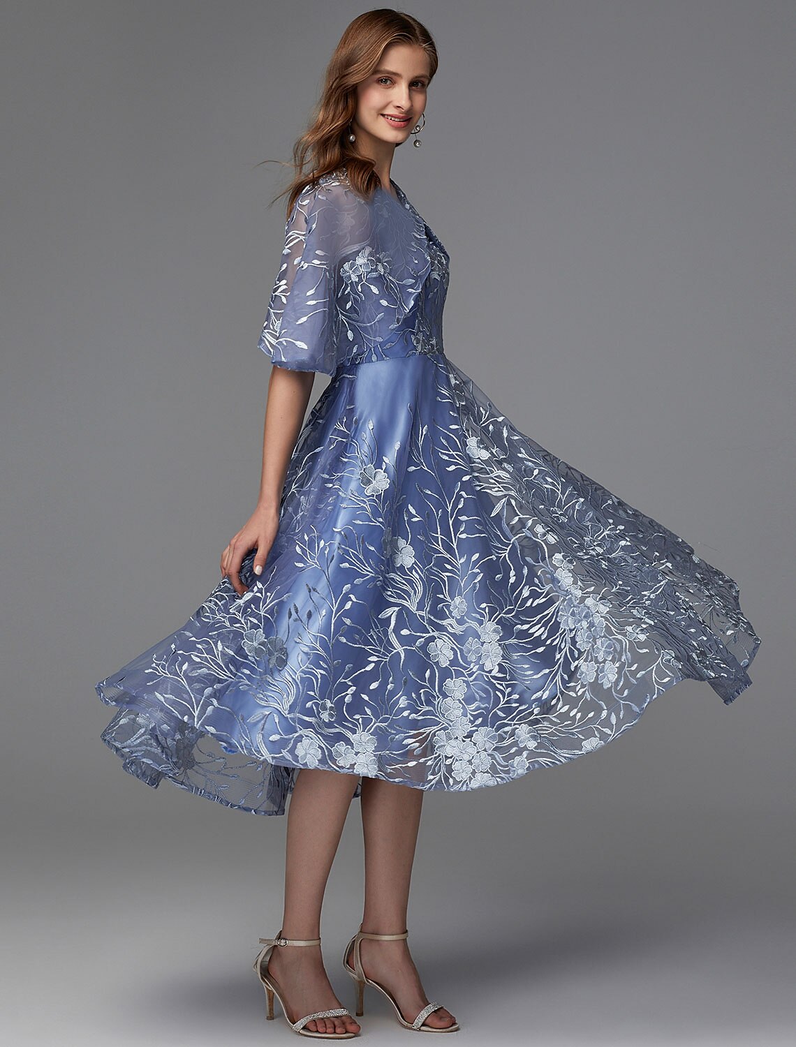 Side profile of a woman in a sleeveless floral tea length dress.