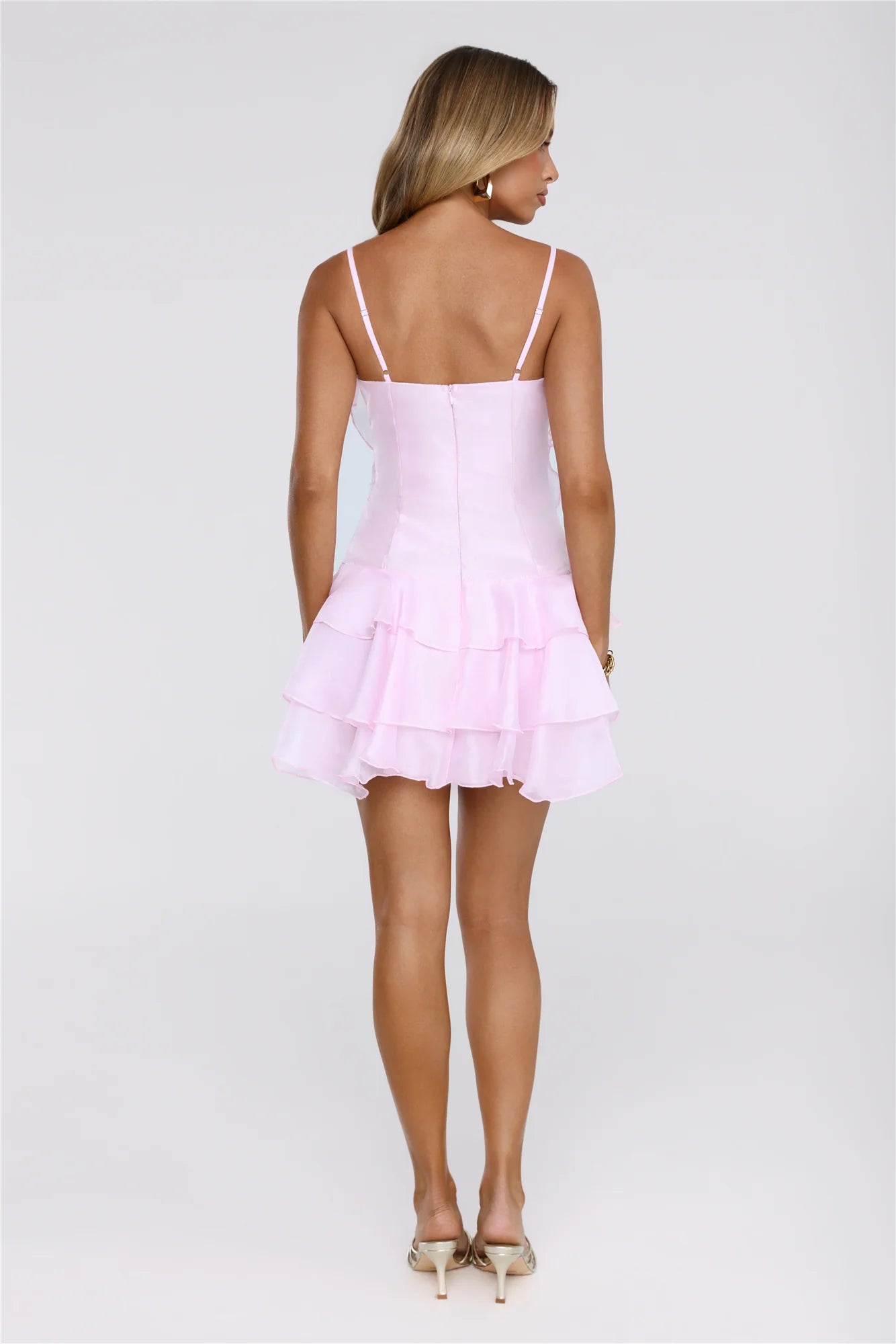 Close-up of floral applique and spaghetti strap on pink dress.