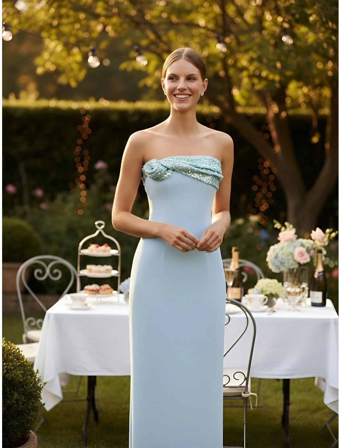 Side view of a model showcasing a strapless, floor-length formal dress with a beaded bow.