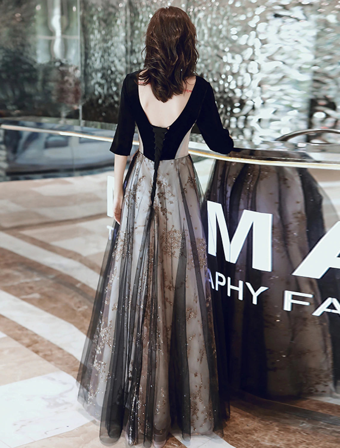 Model wearing a half-sleeve velvet evening dress, showcasing its flow.