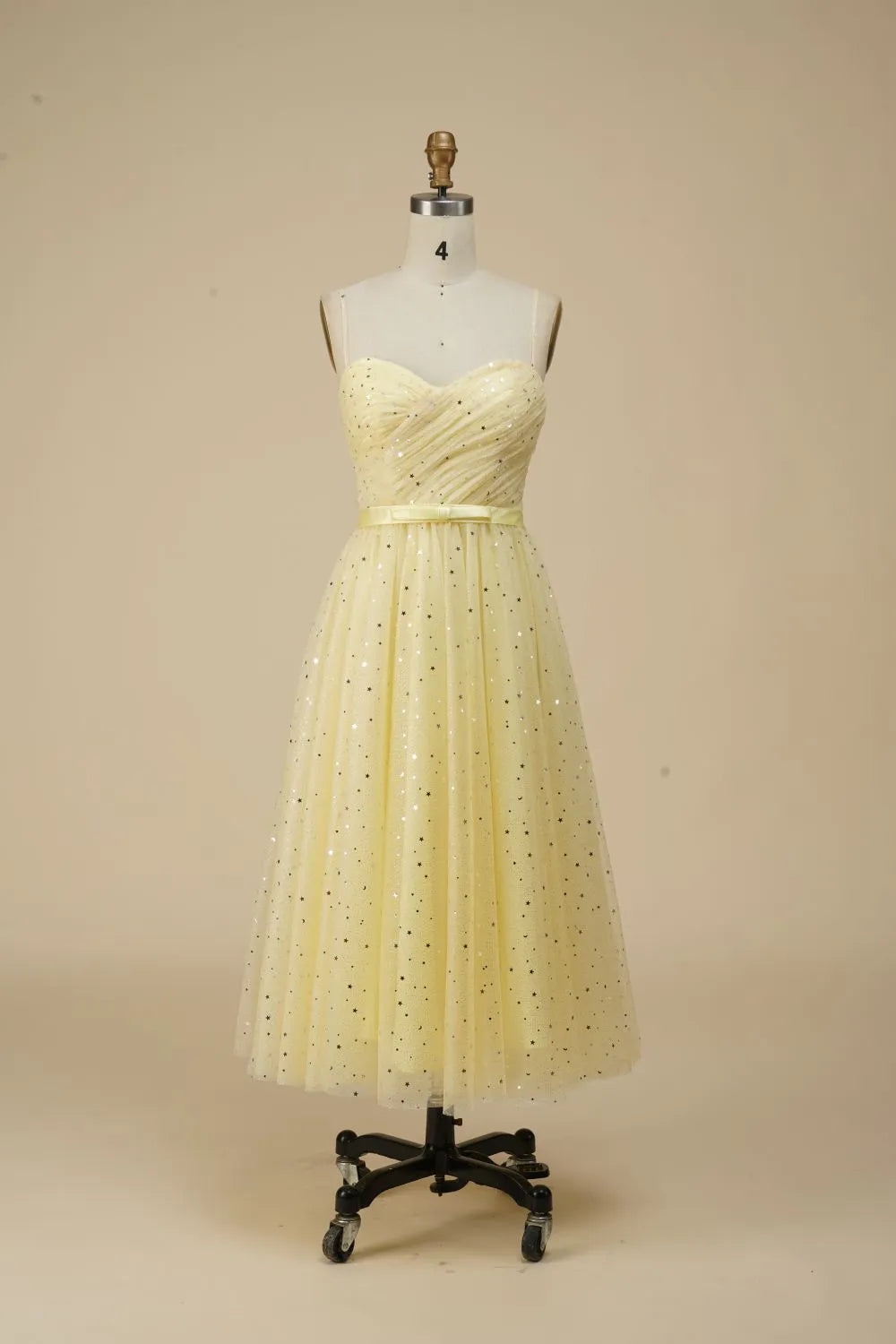 Woman wearing a glittering A-line spaghetti strap party dress with a belt.