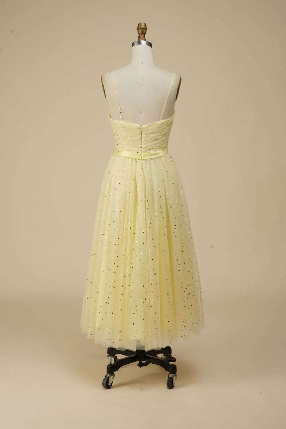 Back view of a woman in a glittering A-line spaghetti strap dress.