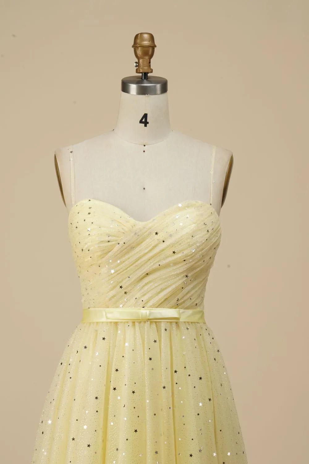 Side view of a woman in a glittering A-line spaghetti strap dress with a belt.