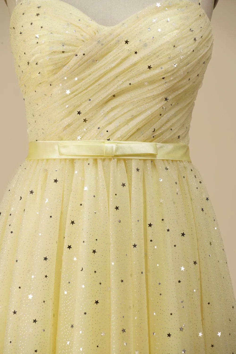 Close-up of the belted waist on a glittering A-line spaghetti strap dress.