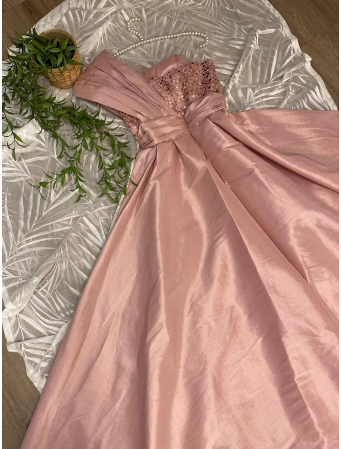 Close-up of the ruched satin and sequin details on the evening dress.