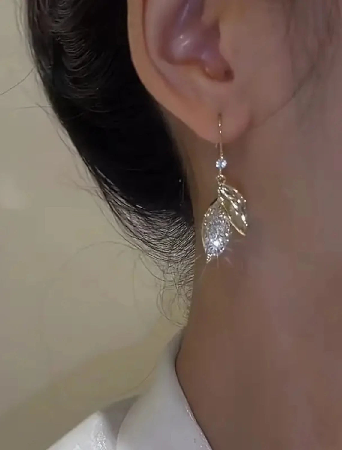 Close-up of a gold leaf drop earring, highlighting texture.