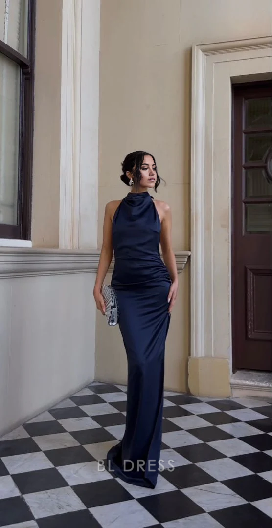 Woman wearing a navy blue satin halter sheath formal gown.