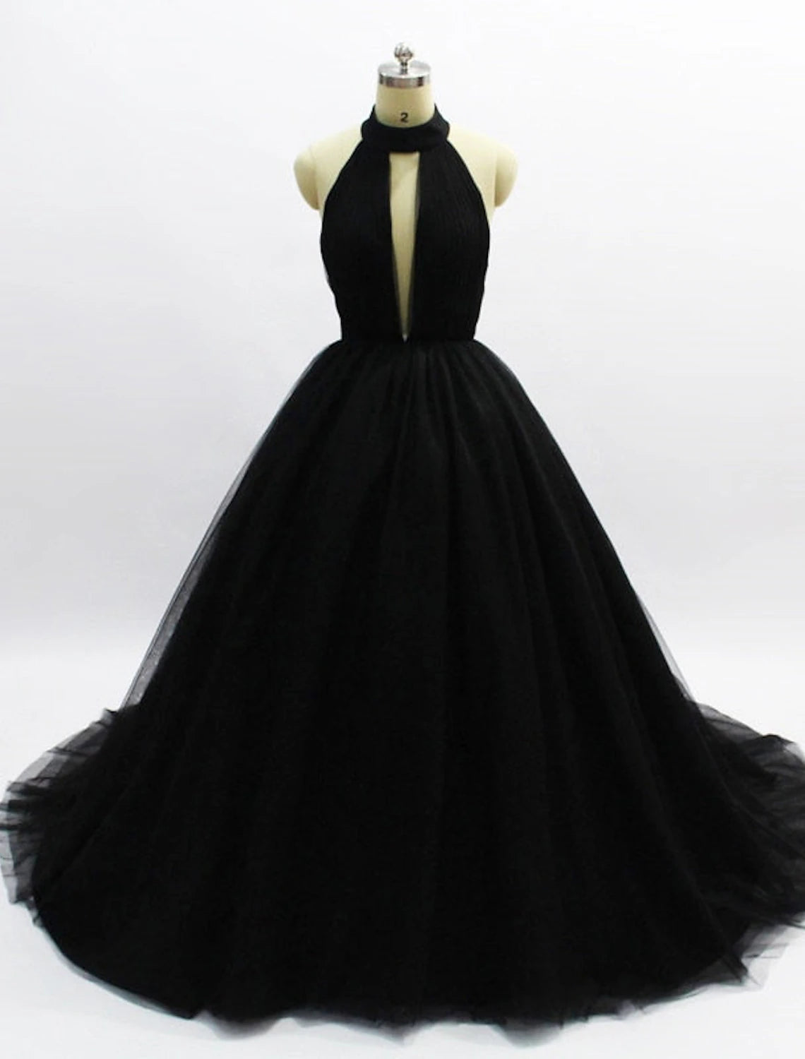 Model wearing a halter neck tulle ball gown with an open back and pleats, front view.