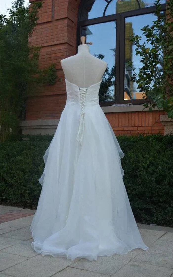 Front view of a white high-low chiffon wedding dress with flowing chiffon skirt and ruffles.