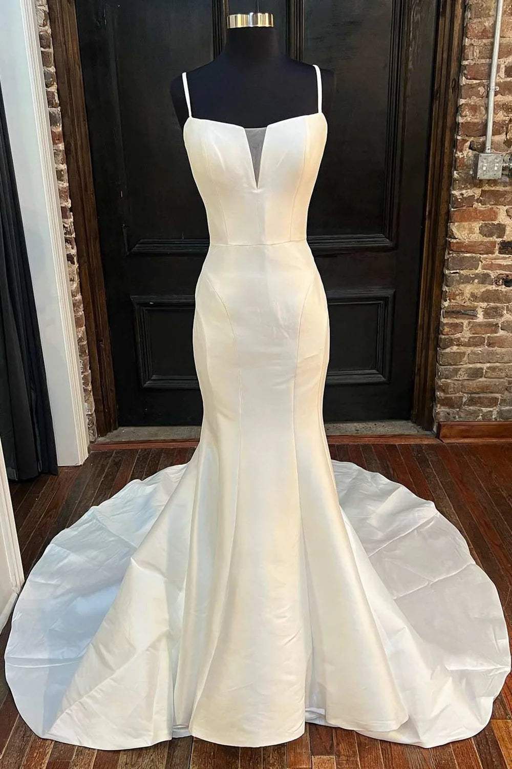 Woman wearing an elegant white high-neck trumpet wedding dress with a front split.
