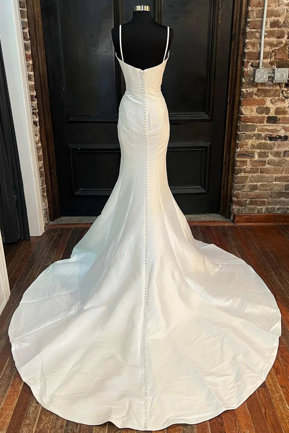 Back view of a woman in a white high-neck trumpet wedding dress with a flowing train.