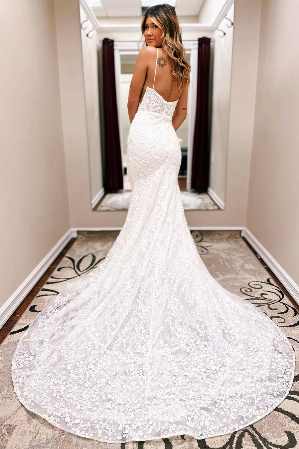 Close-up of the lace detailing and flowing train on an ivory mermaid wedding dress.
