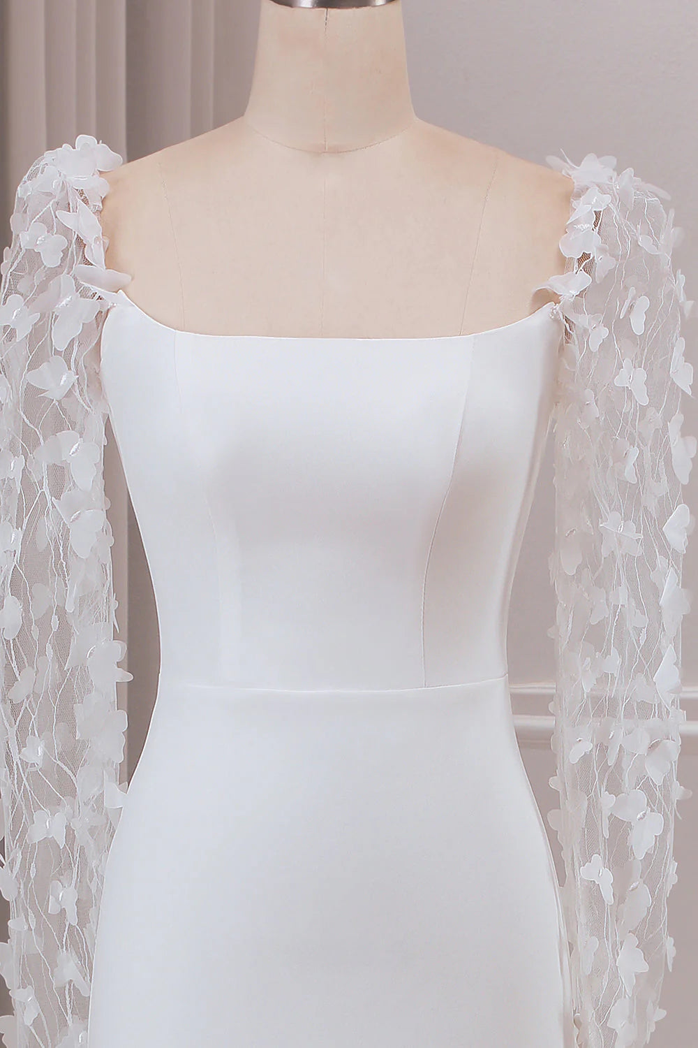 Close-up of 3D appliques and long sleeve on ivory wedding dress.