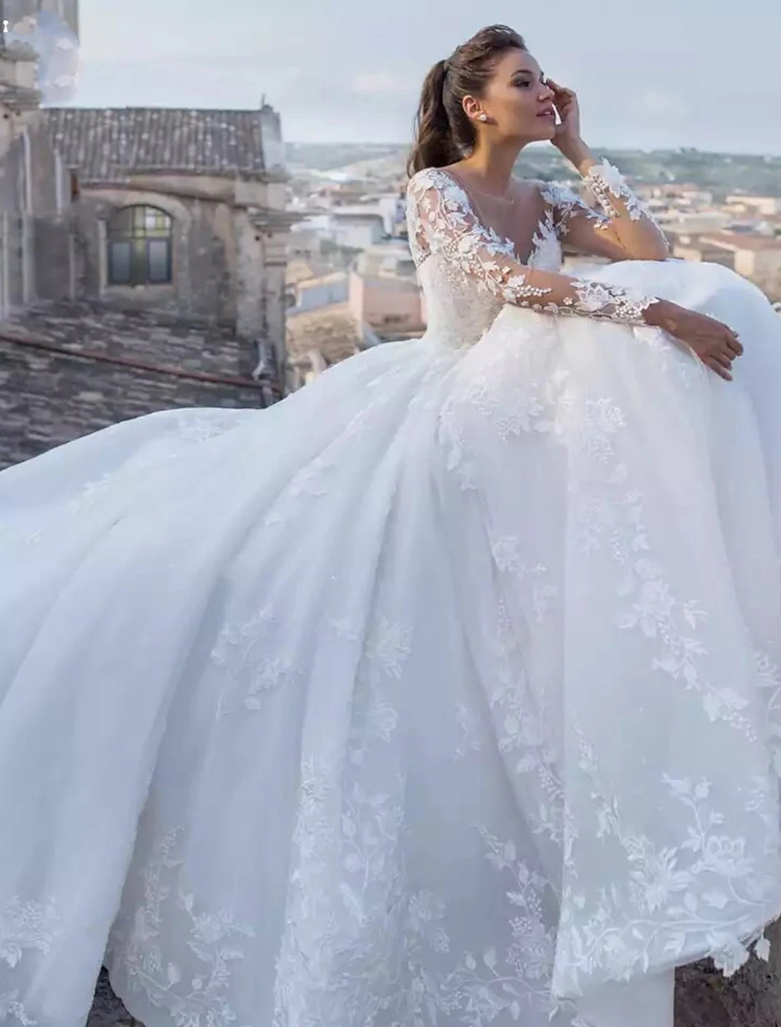 Model wearing an elegant V-neck long sleeve ball gown wedding dress with lace appliques.