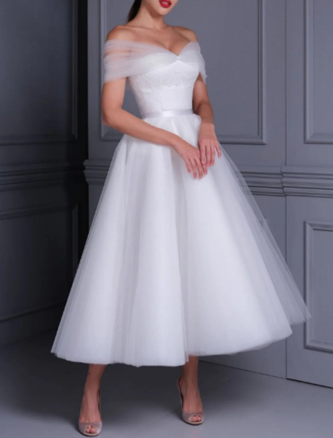 Close-up of a model in a white lace off-the-shoulder ankle-length wedding dress, showcasing the intricate lace details.
