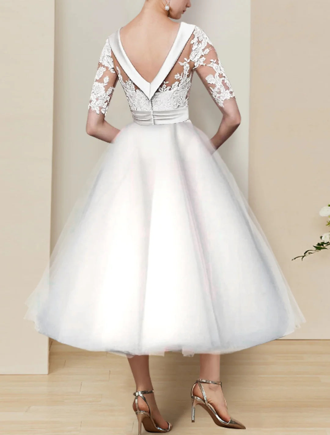 Side view of a bride wearing a lace ball gown tea-length wedding dress with a scoop neck.